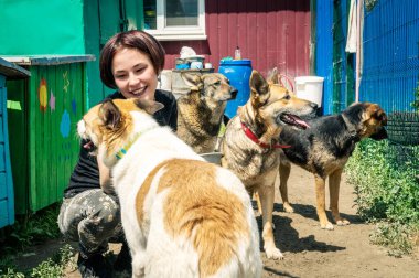 RIVNE, UKRAINE - 21 Haziran 2022. Gönüllülerle kafeste yalnız köpekler. Hayvan barınağı gönüllüsü köpeklerle ilgileniyor. Barınaktaki köpekler. 