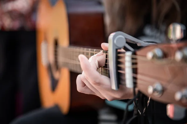 Close-up of woman playing guitar. Hand of woman playing guitar on the street. Music learning