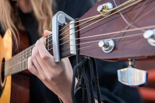 Close-up of woman playing guitar. Hand of woman playing guitar on the street. Music learning
