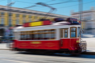 Kırmızı tramvay şehir caddesi boyunca gidiyor. Yolcu kentsel elektrik nakil aracı. Hareket bulanıklığı