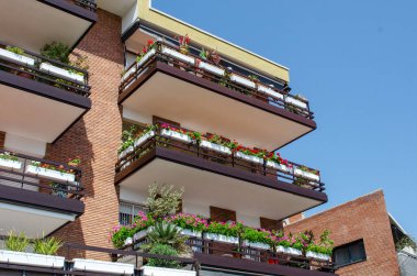 Çiçeklerle süslenmiş bir ev. Çok katlı binanın balkonunda çok güzel parlak renkler var.