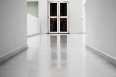 Aydınlık odanın içindeki kapı. Beyaz duvarları ve ışıklı zemini olan boş bir oda.