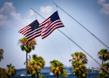 Two American flags flying on a sailboat, blowing in the wind, at Glorietta Bay in Coronado, California.