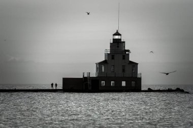 Two people fishing at sunrise on the Lake Michigan pier at Manitowoc, Wisconsin.