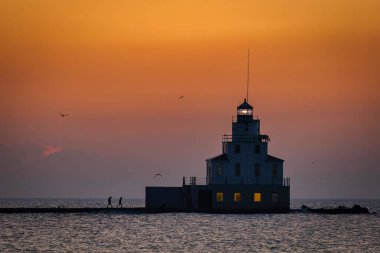 Two people on a sunrise walk to the lighthouse on Lake Michigan at Manitowoc, Wisconsin.