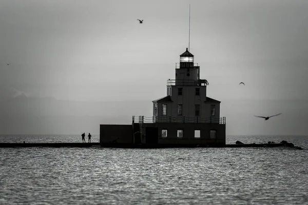 Two people fishing at sunrise on the Lake Michigan pier at Manitowoc, Wisconsin.