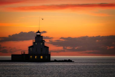 A quiet, red, pre-dawn July morning behind the lighthouse at the north pier on Lake Michigan in Manitowoc, Wisconsin.