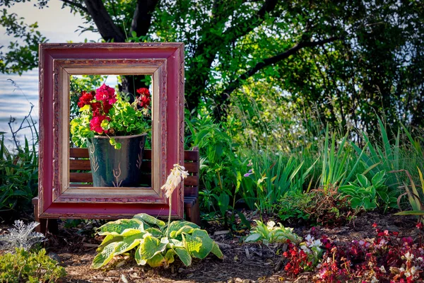 A bucket of flowers inside a picture frame sits in a colorful garden on the Mariner\'s Trail between Manitowoc and Two Rivers, Wisconsin.