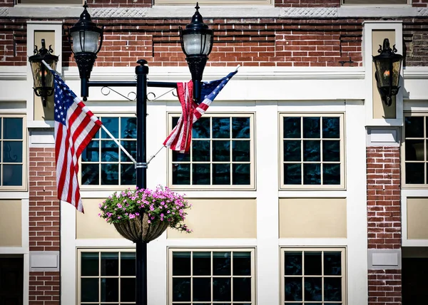 The flags and flowers on a light pole sitting on a city street in Manitowoc, Wisconsin.