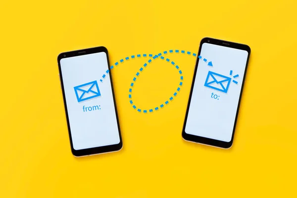 e-posta konsepti Sarı arka planda iki cep telefonu bir çizim yoluyla elektronik posta işlemini gösteriyor.
