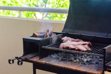Dairenin balkonunda portbalya ızgarası ile barbekü yapmak. Geleneksel Arjantin bifteği. Asado.