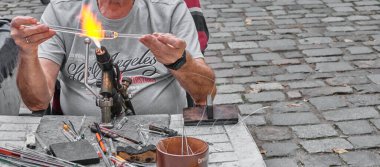 Alevle işlenen sanatsal cam işleme süreci. Olgun cam üfleyicisinin elleri