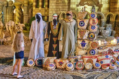 Cami çantalarının yakınındaki meydanda turistler için Mısır hediyelik eşyaları, renkli lambalar, giysili mankenler.