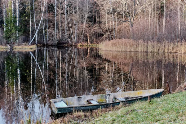 Paisagem de outono. Velho barco de madeira ancorado à costa do lago calmo cercado por floresta. — Fotografia de Stock