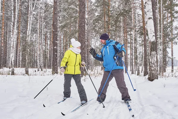 Quarrel of mature couple in winter sportswear are cross-country skiing in snowy forest. — 스톡 사진