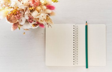 Open blank notebook with turquoise pencil and beautiful bouquet of dried flowers