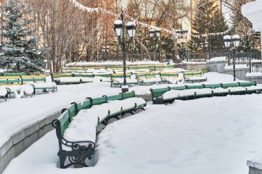Şehir parkının yaz amfi tiyatrosunda karla kaplı ahşap banklar. Kış şehri.