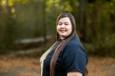 Siyah tişörtlü, uzun saçlı esmer bir kadın.