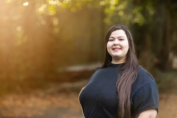 Eine brünette Frau im schwarzen Hemd mit langen Haaren steht draußen — Stockfoto