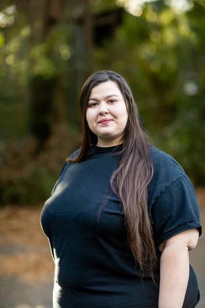 Brunetka w czarnej koszuli z długimi włosami stojąca na zewnątrz — Zdjęcie stockowe