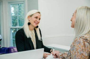 Küçük bir işletme sahibi, bir sağlık merkezindeki müşteri kaydını yaptırıyor.