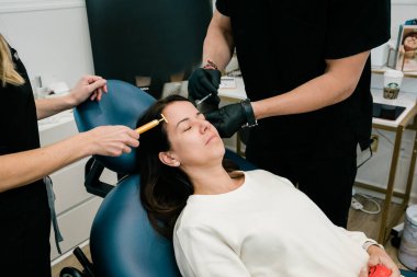 Alnında ve yüzünde botulinyum toksini olan bir kadın. Hem doktor hem de pratisyen hekim tarafından.