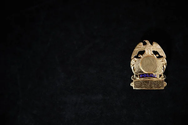 Um distintivo de polícia de ouro indescritível em um fundo preto ith espaço de cópia — Fotografia de Stock