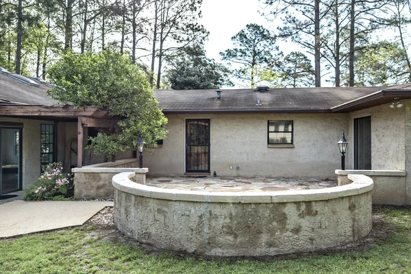 Visão lateral traseira de estilo espanhol marrom estuque e bloco de cinzas casa dos anos 1970 com um pátio circular de pedra — Fotografia de Stock