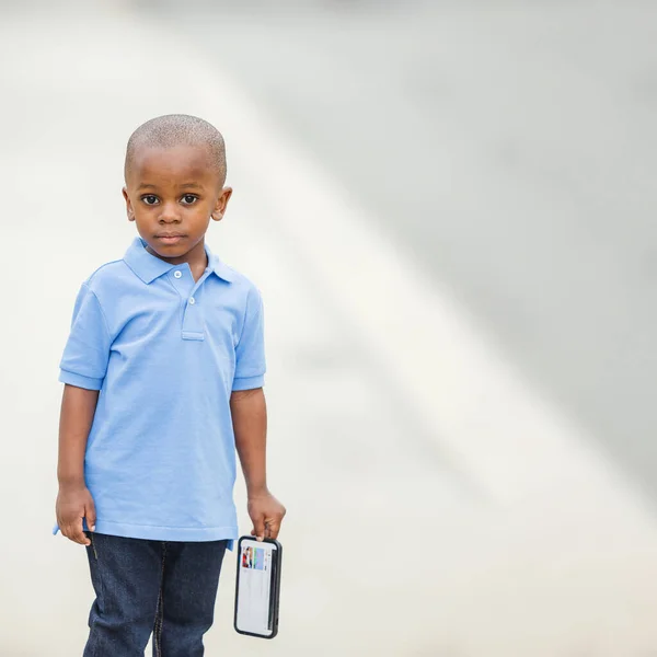 Маленький мальчик, стоящий снаружи с телефоном и грустный. — стоковое фото