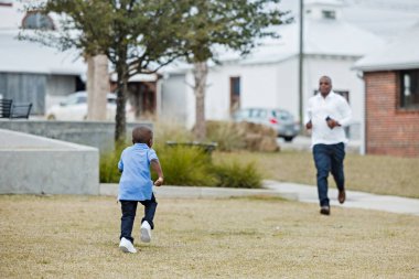 Anaokulu öğrencisi bir çocuk babasının yanına koşuyor.