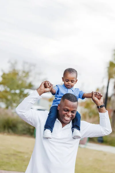 Отец, который держит своего сына дошкольного возраста на плечах — стоковое фото