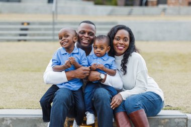 Güzel bir Afro-Amerikalı anne ve baba dışarıda oturmuş oğullarına sarılıyorlar.