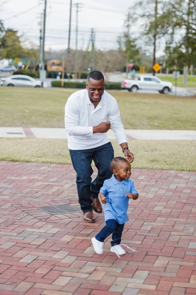 Отец гоняется за своим сыном на улице, пока они играют вместе и сближаются. — стоковое фото