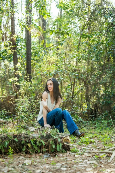 Une belle jeune fille brune sérieuse regardant loin de la caméra vers l'avenir dans une zone boisée au printemps — Photo