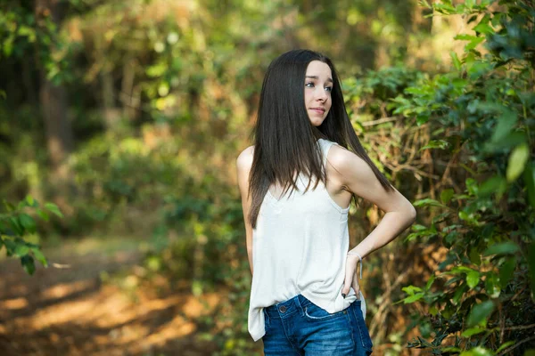 Une belle jeune fille brune sérieuse regardant loin de la caméra vers l'avenir dans une zone boisée au printemps — Photo