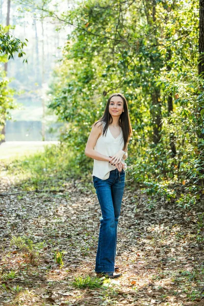 En vacker seriös tonåring brunett flicka tittar bort från kameran mot framtiden i ett skogsområde på våren — Stockfoto