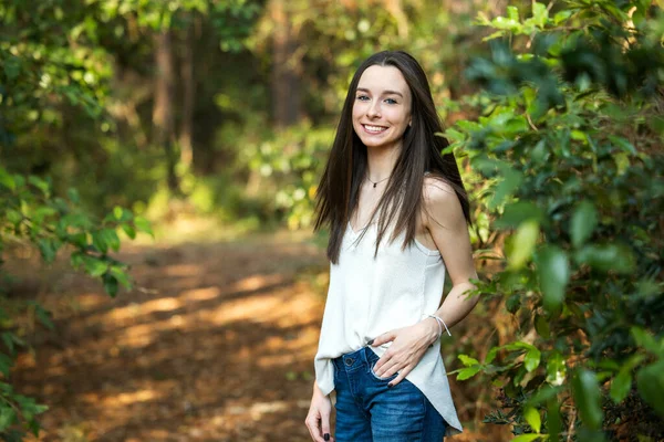 A beautiful happy teenage brunette girl outdoors in a wooded area in the spring — Zdjęcie stockowe