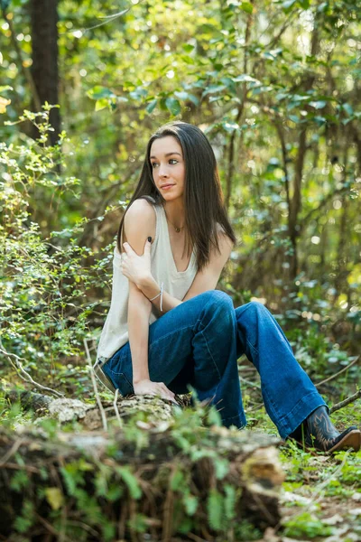 Ein schönes ernstes brünettes Teenie-Mädchen, das im Frühling in einem Waldgebiet von der Kamera in die Zukunft blickt — Stockfoto