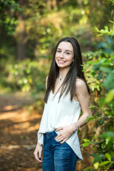 En vacker glad tonåring brunett flicka utomhus i ett skogsområde på våren — Stockfoto