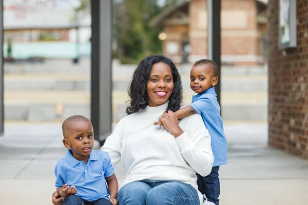 Мать с длинными волосами сидит снаружи с двумя маленькими сыновьями — стоковое фото