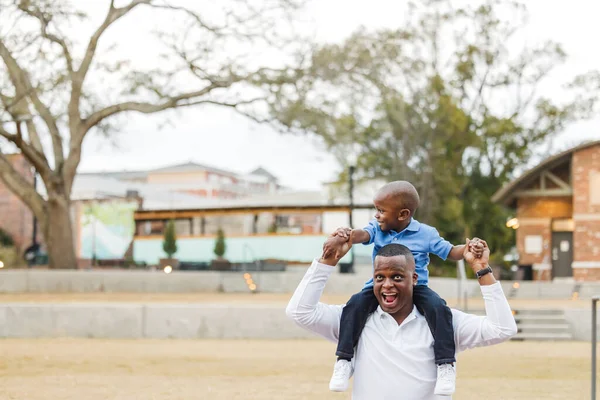 Anaokulundaki oğlunu omuzlarında taşıyan bir baba.