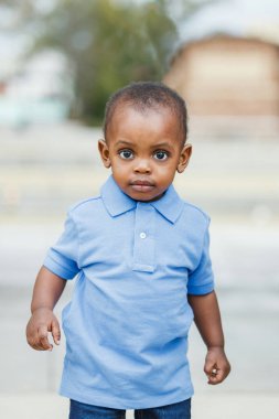 A cute one year old toddler almost preschool age African-American boy who looks surprised