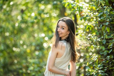 A beautiful happy teenage brunette girl outdoors in a wooded area in the spring spinning around with her hair flying,
