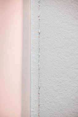 Yapılı gri duvarda bir çatlak var. Köşedeki alçıpan tamir edilmesi gereken yeni bir inşaat evinde buluşuyor..