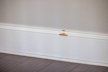 MDF malzemelerinden tamir edilmesi gereken kırık bir parça olan yeni bir inşaat evinin beyaz boyalı süpürgeliği..