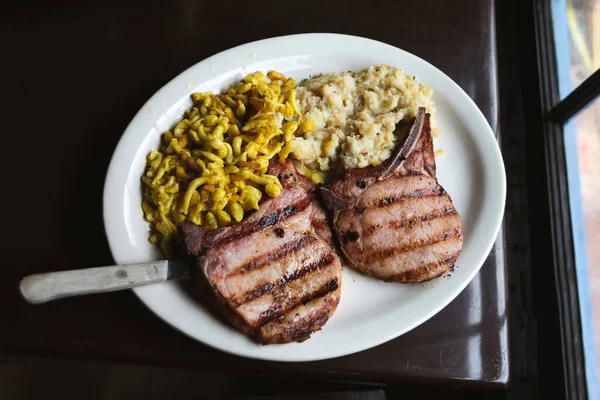 Smoked and grilled porkshops with a side of cheese spaetzle and mashed potatoes for dinner plate as a typical German dinner meal.