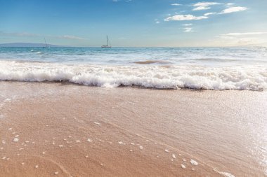 Maui Hawaii beach coastline of sand, sun, and blue water with crashing.