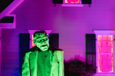 Cadılar Bayramı 'nda mor ışıklı bir eve karşı yeşil parlayan korkunç, gerçek boyutta Frankenstein kokusu alan bir canavar..