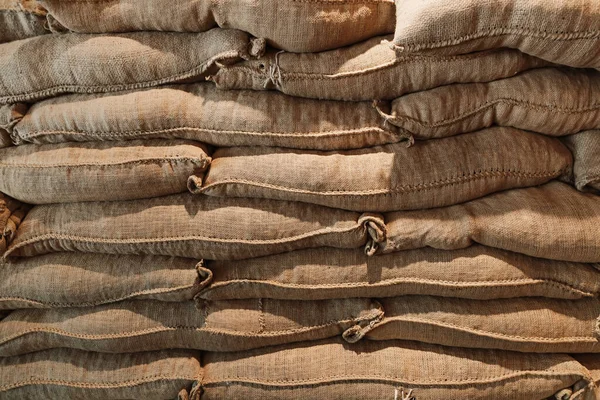large burlap canvas bags of coffee beans stacked up in a local coffee shop or manufacturer or store.