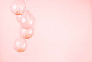 A monochromatic peach pink confetti clear balloons against a light pink backdrop.